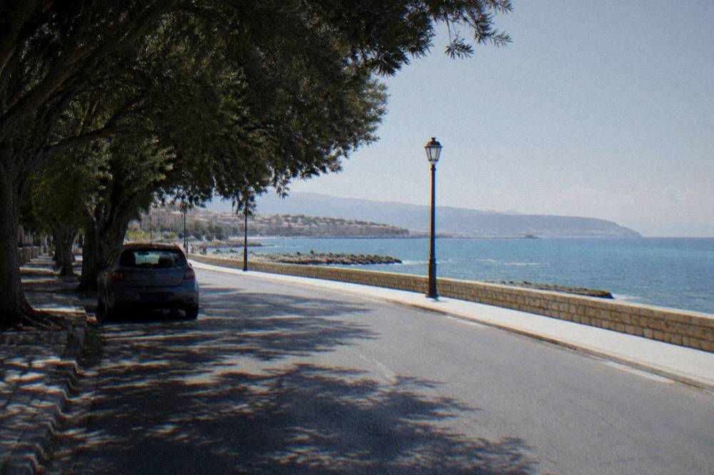 Empty winding road along a coastline with a parked car and sea view