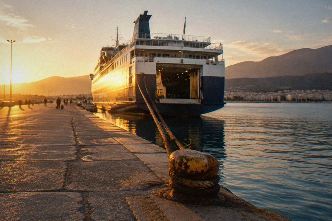 A large overnight ferry moored at a Greek port in the early morning light