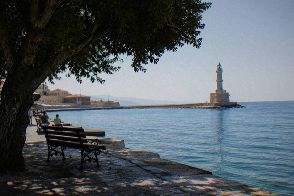 A historic harbour with a stone lighthouse at the end of a long mole at sunrise