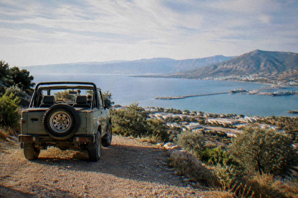A small open off-road vehicle parked on a dirt track above a coastal valley