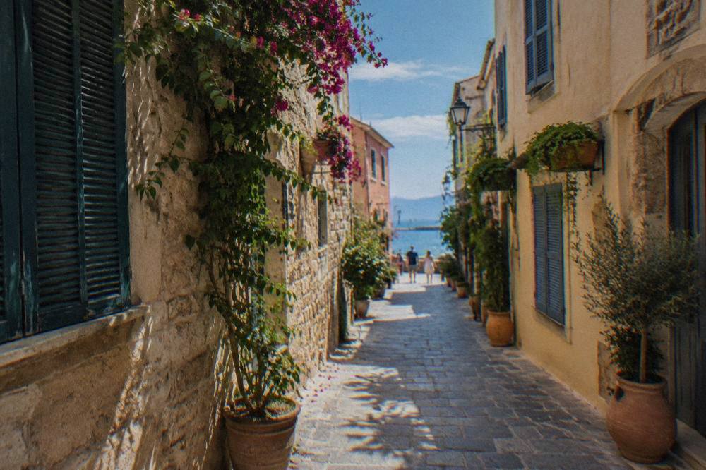 A narrow stone-paved lane in Chania Old Town with shuttered buildings and hanging plants