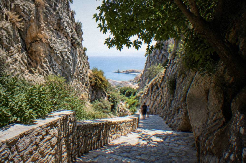 A stone footpath descending through a steep rocky gorge with cliffs rising on both sides