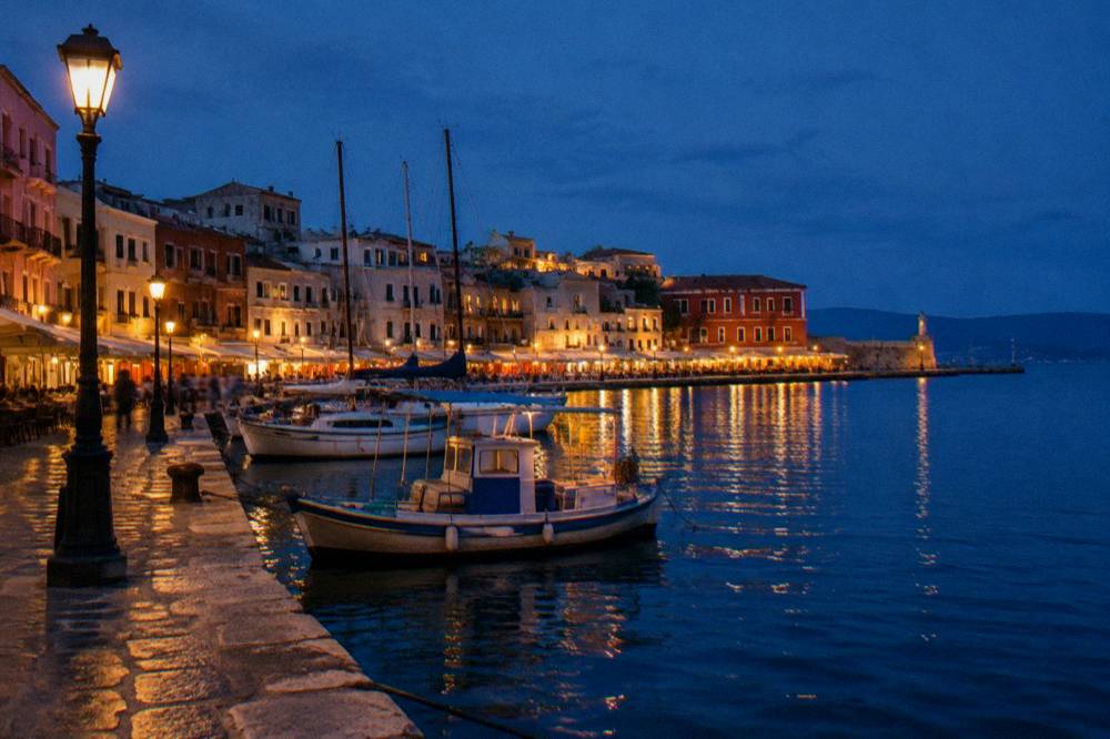 The Venetian harbour of Chania at blue hour with warm lamps reflecting on the dark water