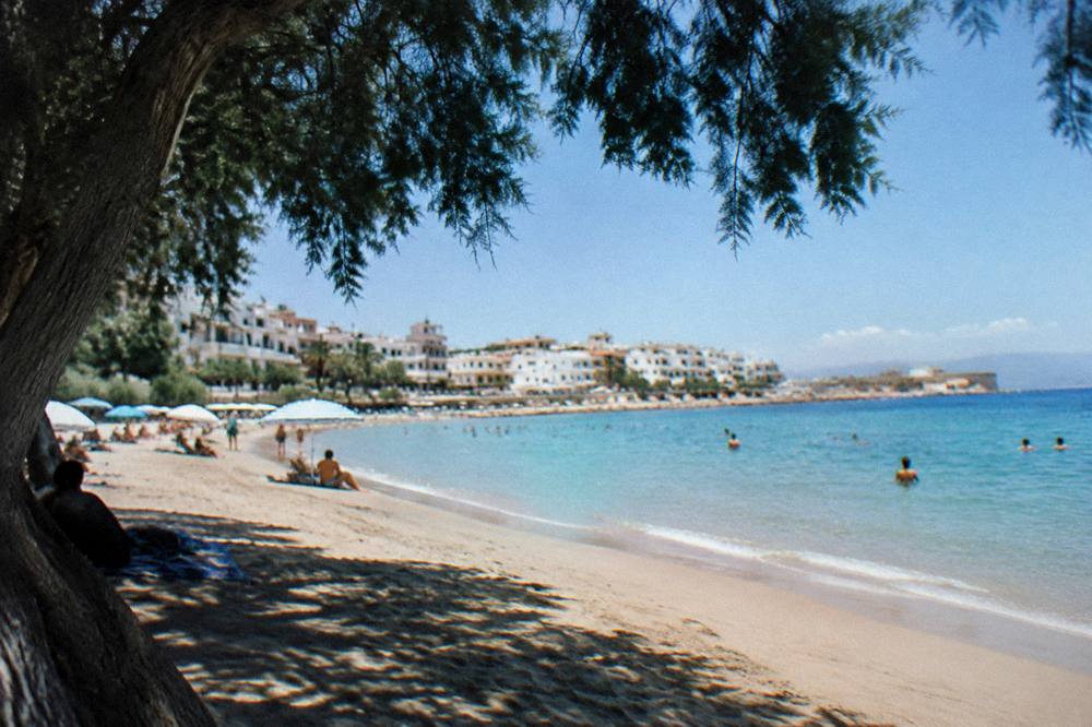 The sandy Nea Chora beach in Chania with shallow turquoise water and a few swimmers