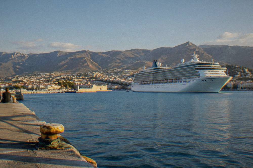 A cruise ship at anchor in Souda Bay with the city of Chania rising behind the shoreline