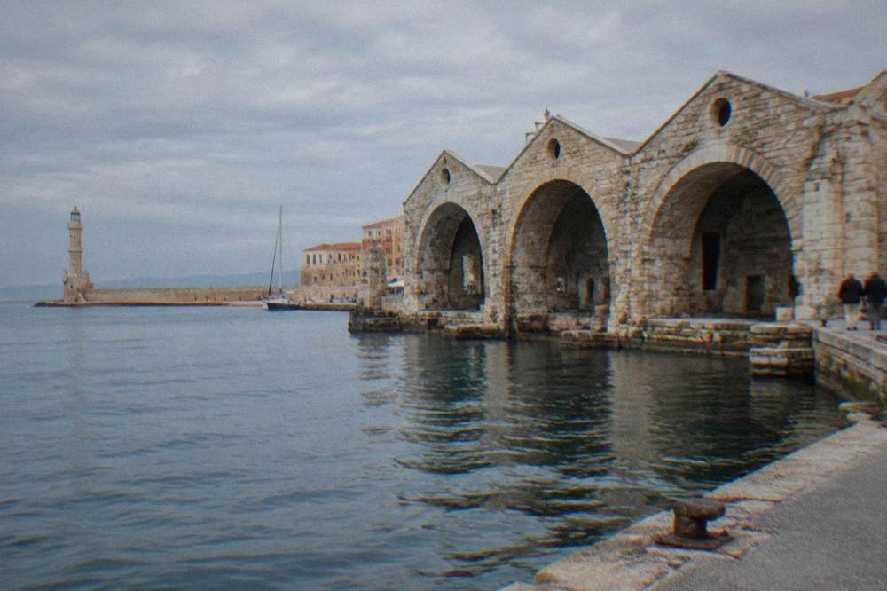 The stone arches of the Neoria shipyards along the Chania harbour front in afternoon light