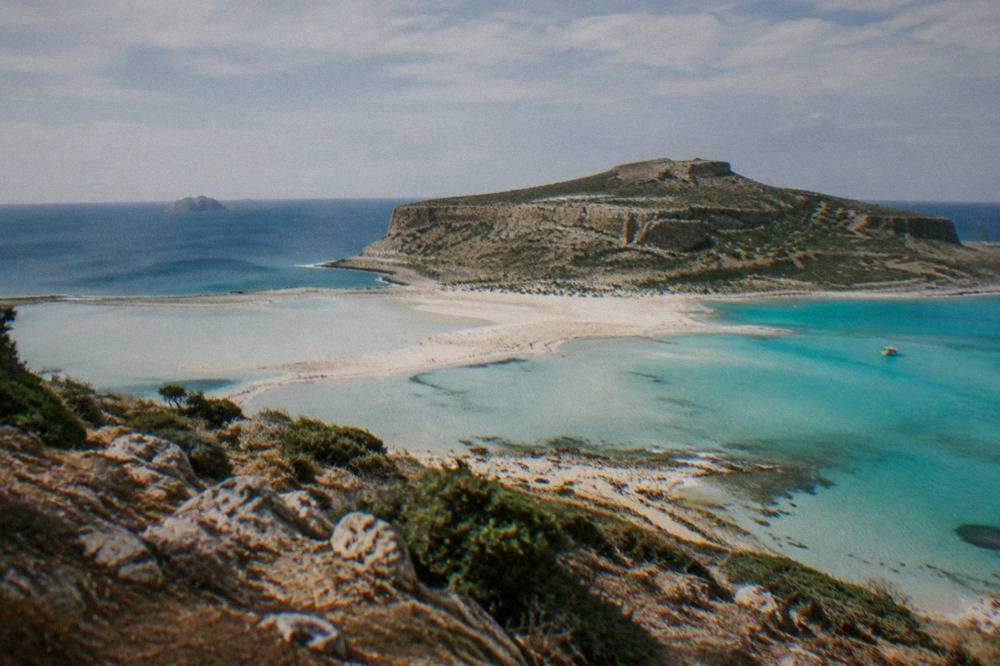 The turquoise shallows and pale sand of Balos Lagoon seen from the headland above