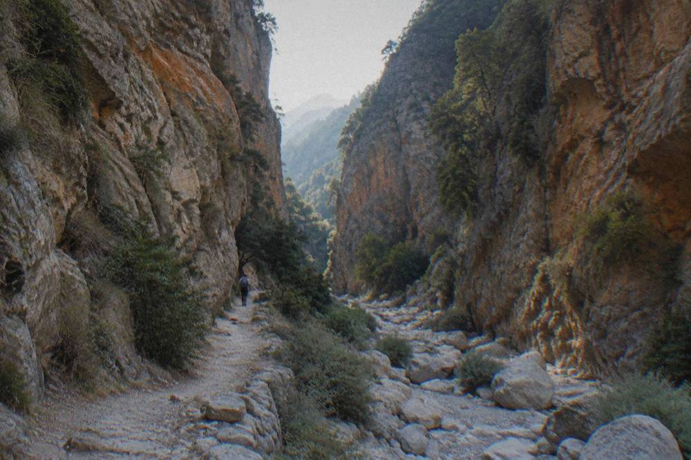 Steep rock walls of a Cretan gorge with a narrow rocky footpath beside a dry stream bed