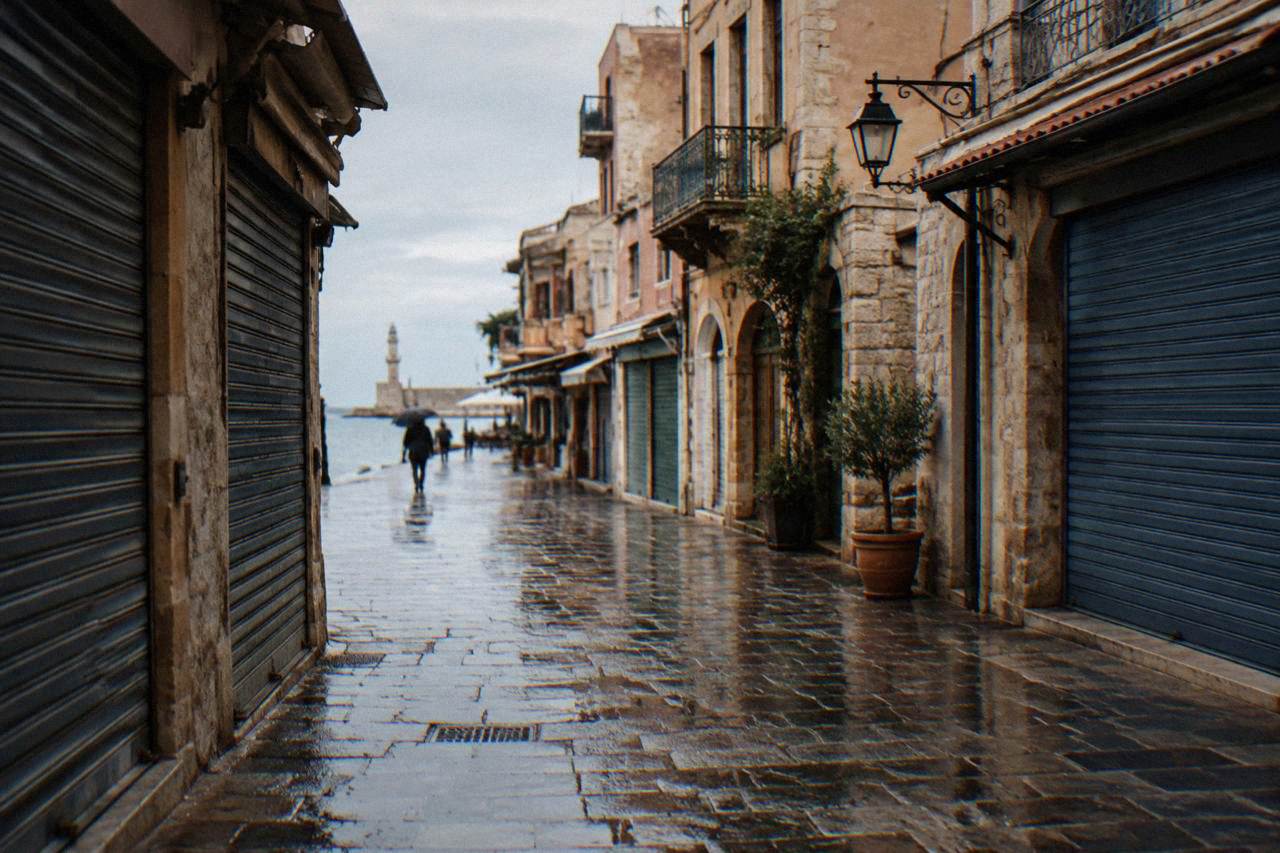 Rainy street in Chania Old Town with wet stone paving and closed shop shutters