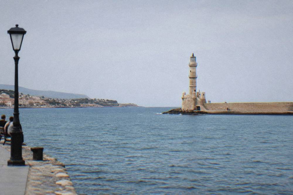 The lighthouse of Chania standing at the end of the harbour breakwater under a clear sky