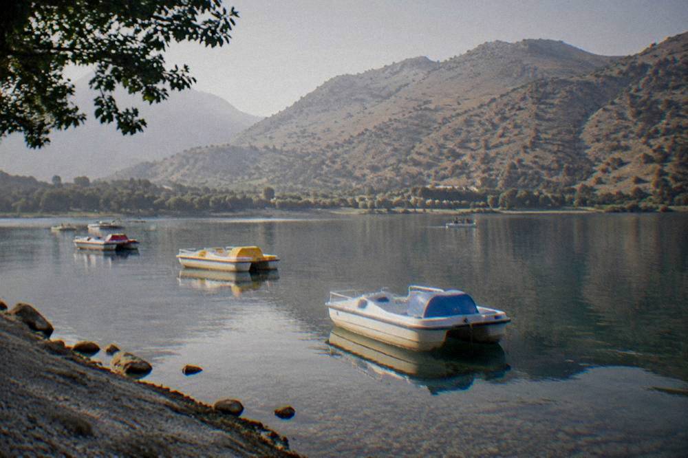Pedal boats resting on the still water of Lake Kournas with hills behind