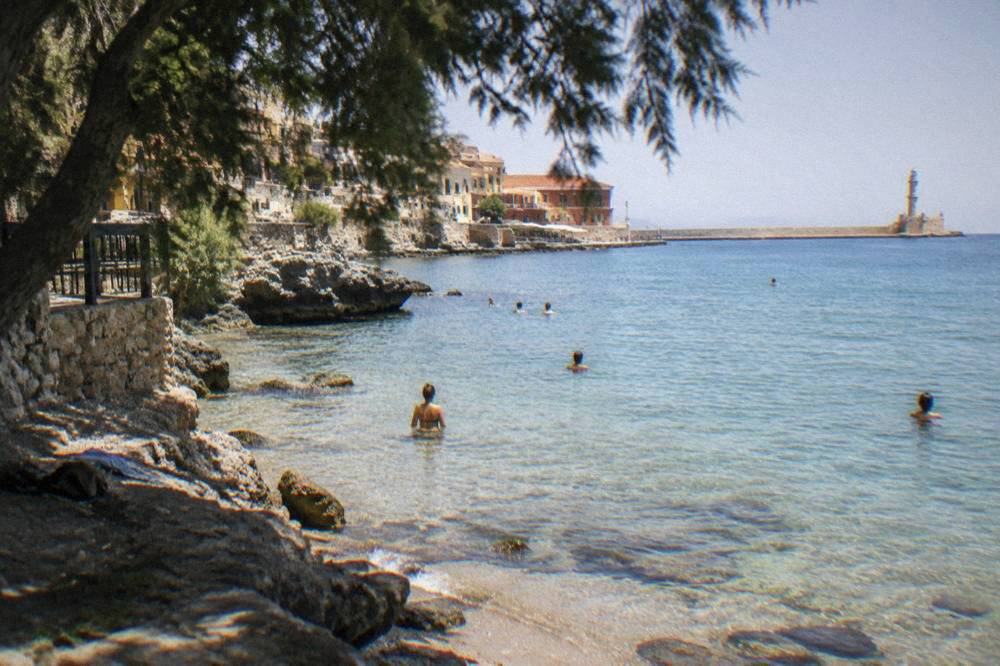 Swimmers in clear shallow water at a small cove near Chania