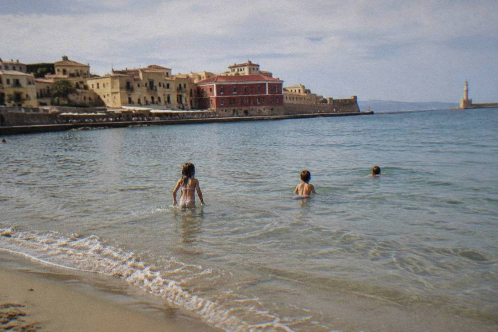 Children swimming in shallow water at a sandy beach near Chania