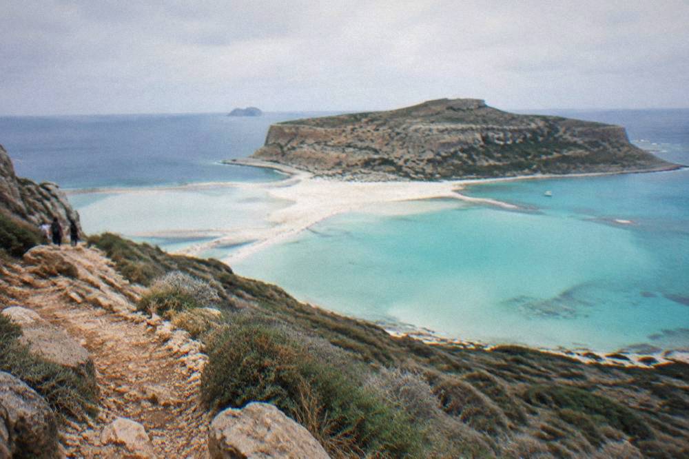 The turquoise shallows and pale sand of Balos lagoon seen from the cliff path