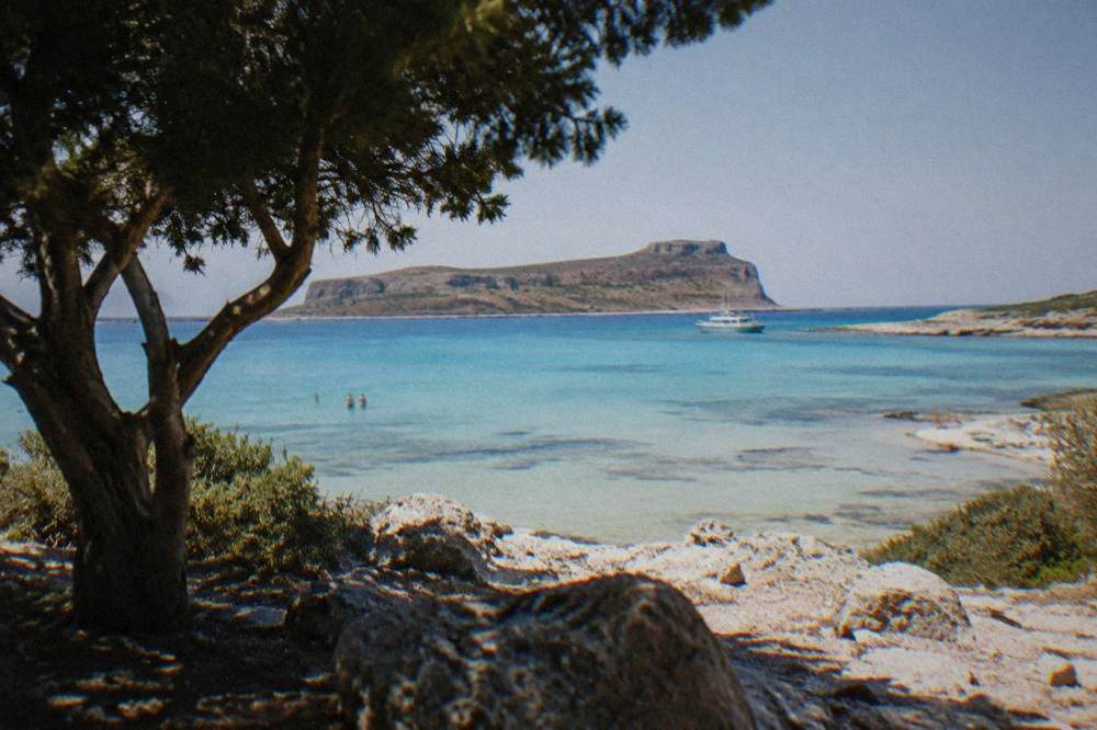A boat anchored off the low island of Gramvousa under a clear sky