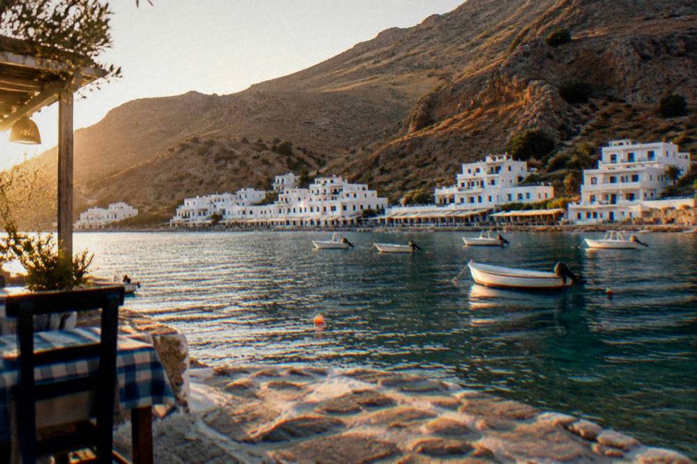 White buildings of Loutro village at the edge of the sea below bare hills